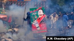 Supporters of former Prime Minister Imran Khan take cover after riot police fired tear gas to disperse them during clashes in Lahore on March 15.