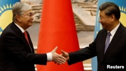 Глава Китая Си Цзиньпин (справа) и президент Казахстана Касым-Жомарт Токаев обмениваются рукопожатием во время церемонии подписания документов в Сиане, Китай, 17 мая 2023 года