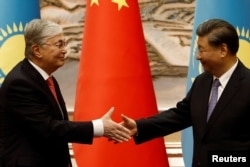 Hszi Csin-ping kínai elnök (jobbra) és Kaszim-Zsomart Tokajev kazah elnök kezet fog a Kína–Közép-Ázsia-csúcstalálkozót megelőző aláírási ceremónián a kínai Hszianban 2023 májusában