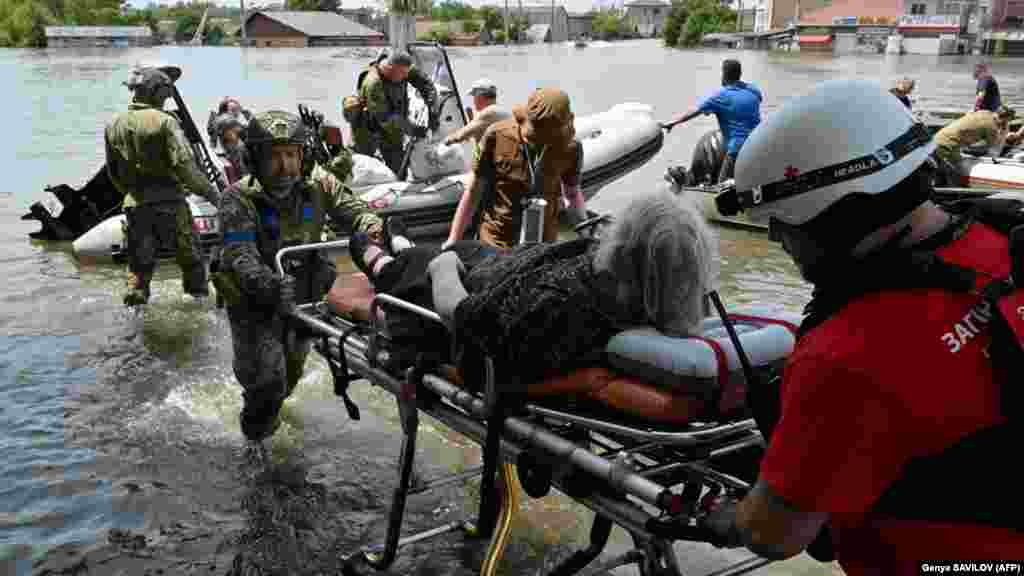 Ukrainian soldiers help unload a local resident from a boat during an evacuation from a flooded area in Kherson. Authorities said that several thousand people were evacuated despite&nbsp;Russian shelling from across the Dnieper River.