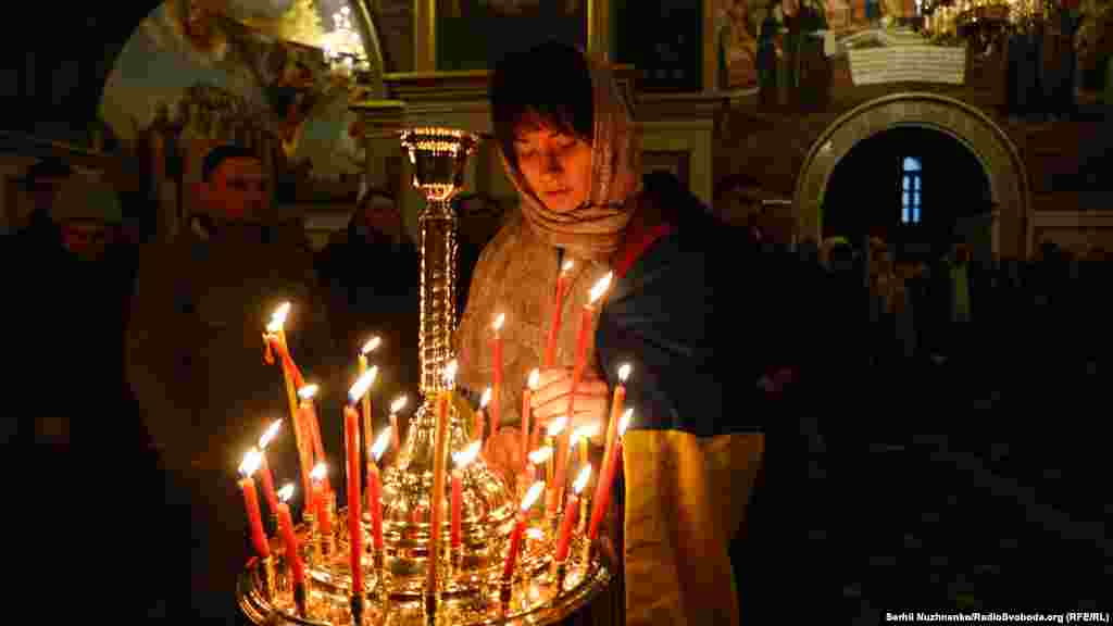 Вірянка з прапором України в Успенському соборі Києво-Печерської лаври запалює свічку, де вперше відбулося Великоднє богослужіння Православної церкви України