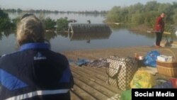 Жители затопленного села в Херсонской области, сидя на крыше, ожидают эвакуации