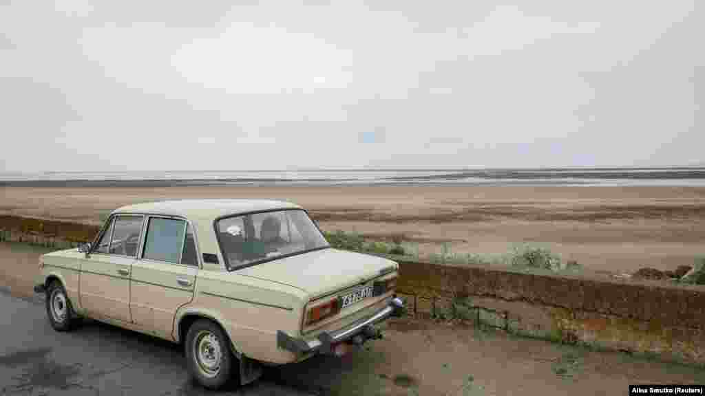 A car drives by the nearly empty Kakhovka reservoir.&nbsp; With water levels expected to stay critically low for the coming weeks, 700,000 people in the Kherson region are facing a water shortage.&nbsp;