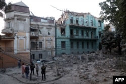 Residents stand next to the buildings damaged as a result of a Russian missile strike in Odesa on July 23.