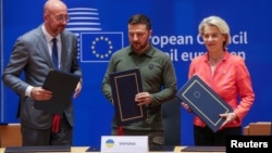 Președintele Consiliului European Charles Michel (stânga), președintele ucrainean Volodimir Zelenski și președintele Comisiei Europene Ursula von der Leyen, la ceremonia de semnare la Bruxelles, pe 27 iunie.