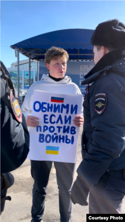 Poliștii îl iau la întrebări pe Nikita Gorbunov în timpul protestului său din 19 martie.