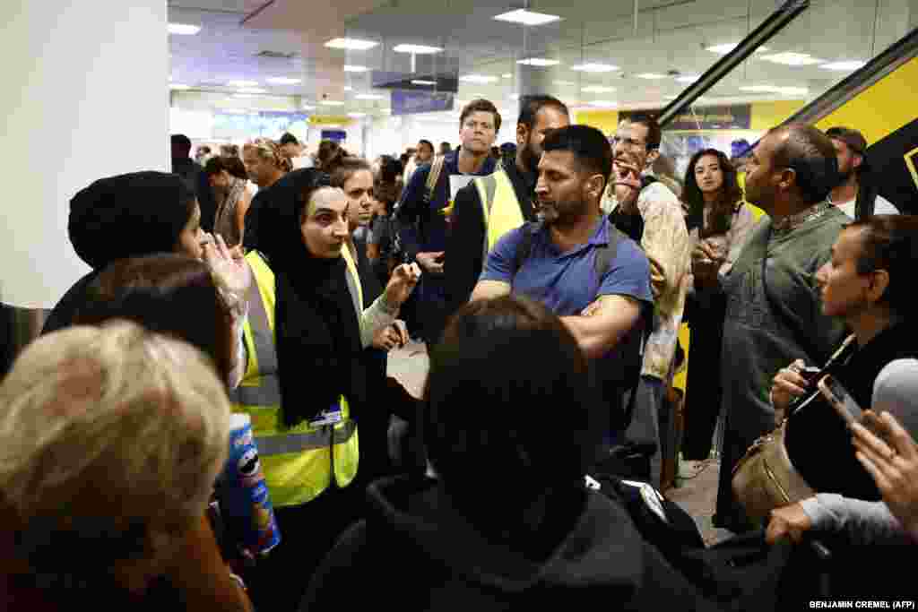 At Gatwick Airport, an airport staff member advises passengers that some flights have been cancelled. Airports including London Luton, Belfast, and Edinburgh warned of longer waiting times for passengers.