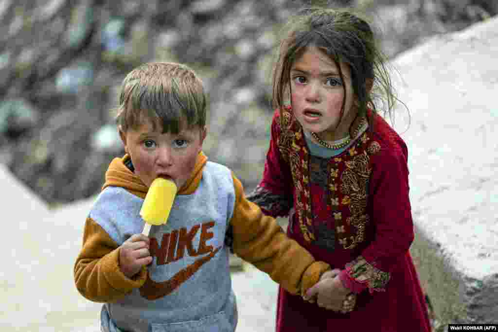 An Afghan boy eats a frozen treat with his sister on the outskirts of Kabul.