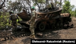 Ukrainian troops inspect a destroyed Russian armored vehicle on June 14 in the Donetsk village of Storozheve, which Kyiv claims to have liberated.