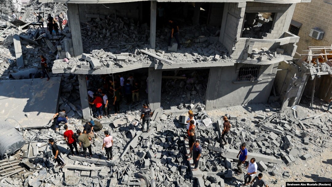 Palestinieni se adună la locul loviturilor israeliene asupra unor case din Rafah, în sudul Fâșiei Gaza, 17 octombrie 2023.