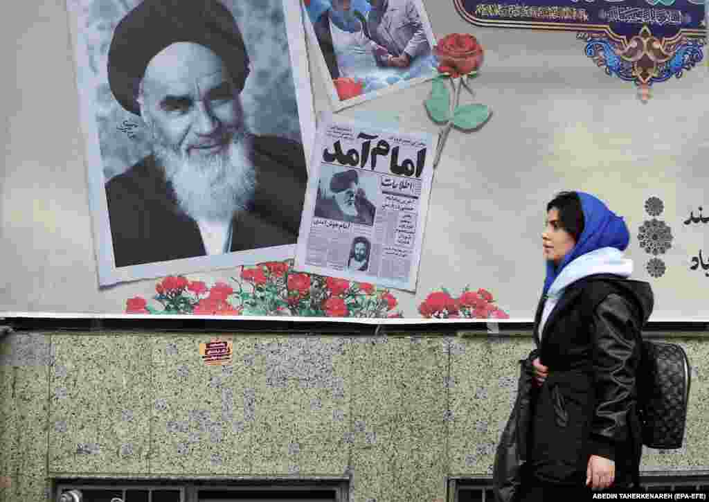 An Iranian woman walks past a picture of the late Supreme Leader Ayatollah Ruhollah Khomeini as the country marks the 45th anniversary of Khomeini&#39;s return from his Paris exile, in Tehran on February 1. Iran will celebrate the 45th anniversary of its revolution on February 11.