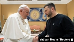 Papa Francisc (stânga) dă mâna cu președintele ucrainean Volodimir Zelenski la Vatican, 13 mai 2023.