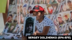 A boy holds up a photo as relatives and friends of Ukrainian missing soldiers and prisoners of war attend a protest in Kyiv on August 4.