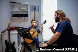 Ledion Halitaj duke mbajtur orën e kitarës me mësuesin e tij, Erhan Mujka.