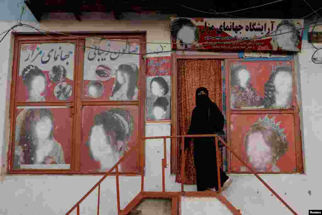A woman enters a beauty salon in Kabul where the ads featuring women have been defaced. Women&#39;s faces have been artlessly deleted from advertisements and murals around the country. &nbsp;