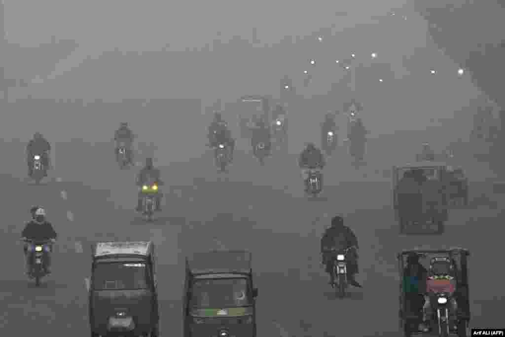 Commuters make their way along a street amid dense smog in Lahore, Pakistan.