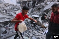 Юноша несет в пакете питы через развалины дома в Хан-Юнисе на юге сектора Газа после израильского авиаудара, 10 октября 2023 года