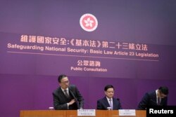 Sekretar pravosuđa Hong Konga, Paul Lam, izvršni direktor John Lee i sekretar za sigurnost Chris Tang Ping-keung na konferenciji za medije povodom zakona član 23, 30. januar 2024.