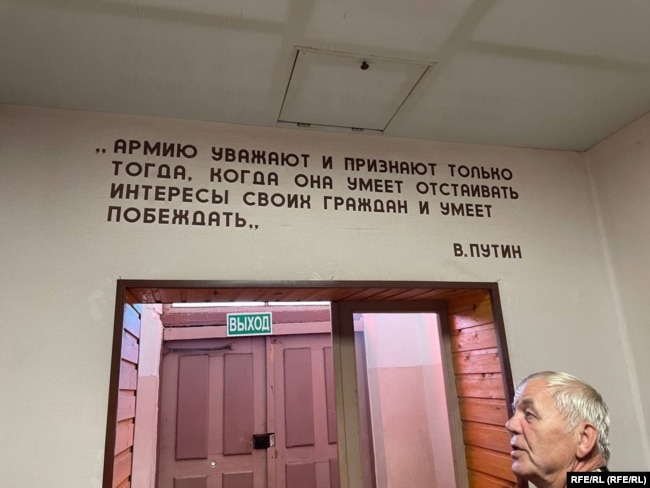 Виктор Приступа в сградата на военния музей ма фона на цитат на Владимир Путин, изписан на стената. Той гласи: "Армията е уважавана и призната само когато умее да защитава интересите на своите граждани и знае как да побеждава."