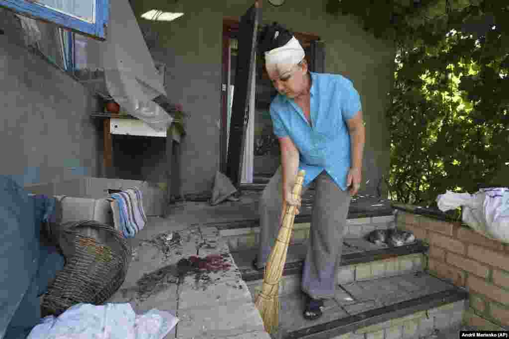 A woman wounded in a Russian missile attack sweeps debris from bloodstained steps in the village of Kindrashchivka in Ukraine&#39;s Kharkiv region.&nbsp;