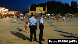 На этой фотографии, сделанной 15 июля 2023 года, изображены полицейские, стоящие на страже главной площади Кашгара в северо-западном регионе Синьцзяна Китая.