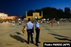На этой фотографии, сделанной 15 июля 2023 года, изображены полицейские, стоящие на страже главной площади Кашгара в северо-западном регионе Синьцзяна Китая
