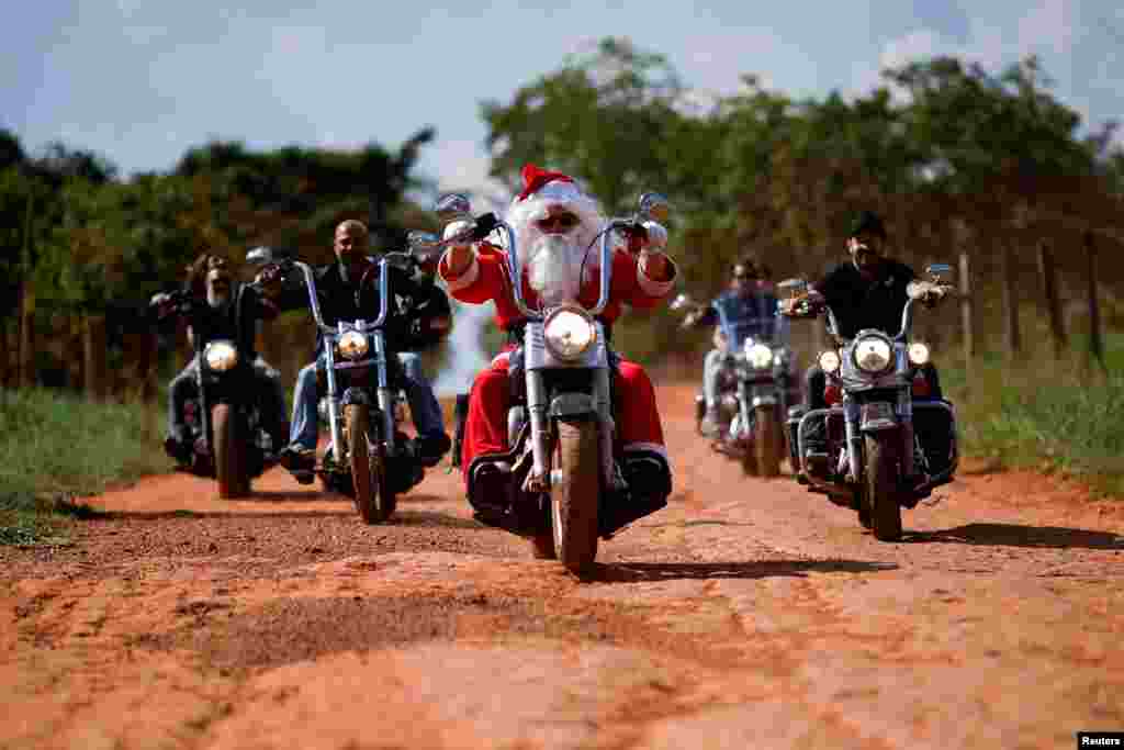 Motociklist Helton Garcia, odjeven u Djeda Mraza, vozi motocikl kako bi podijelio darove djeci u seoskoj školi u Santo Antonio do Descoberto, država Goia, Brazil, 10. decembra 2023.