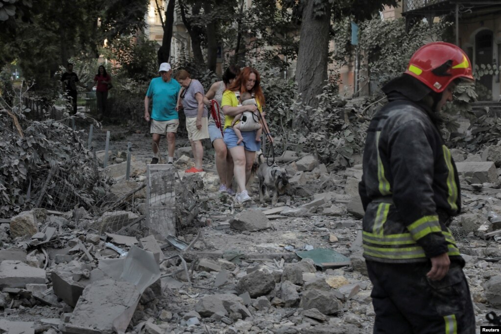 I residenti locali camminano tra le rovine di un edificio residenziale distrutto durante gli attacchi missilistici russi