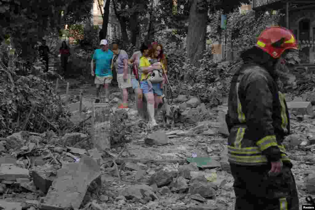 Localnicii merg printre dărâmături la locul unei clădiri rezidențiale avariate în timpul atacurilor cu rachete rusești, pe fondul atacului Rusiei asupra Ucrainei, în Odesa, Ucraina, 23 iulie 2023