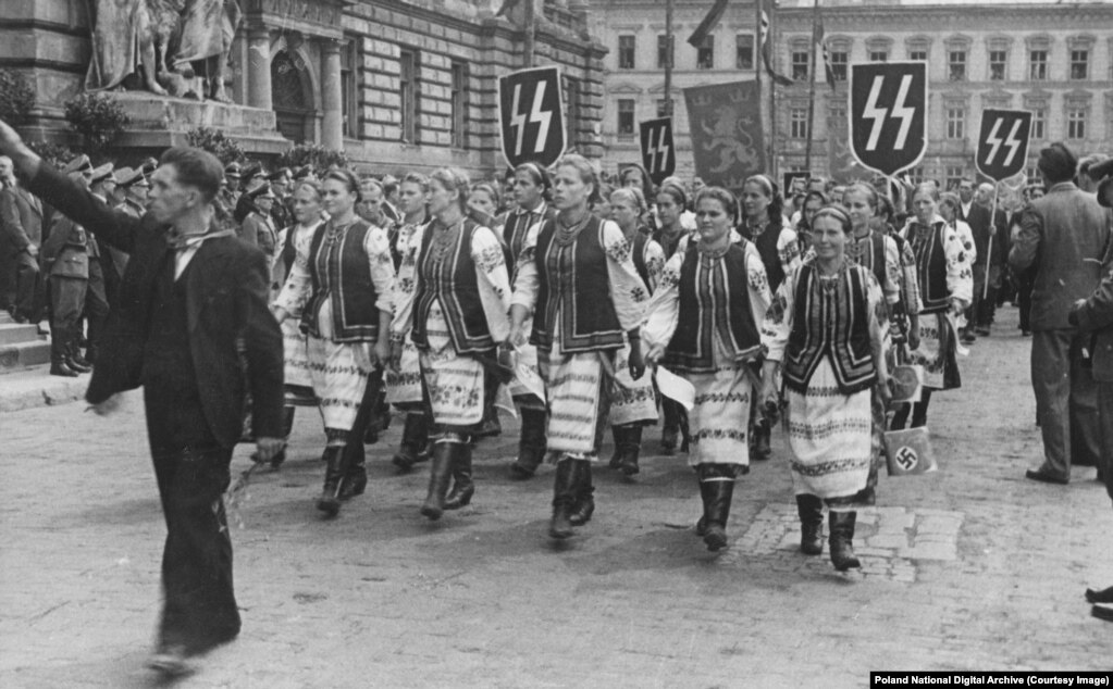 Gratë ukrainase me veshje tradicionale duke kaluar nën banderola naziste në Lviv gjatë një vizite zyrtare nga Hans Frank, udhëheqësi gjerman i Polonisë së pushtuar nga nazistët. Shumë nacionalistë ukrainas patën qëndrimin "armiku i armikut tim është miku im" ndaj pushtimit nazist, duke u dhënë meritën gjermanëve për dëbimin e bolshevikëve komunistë. Disa ukrainas morën pjesë aktive në vrasjet masive të hebrenjve, ndërsa të tjerë, "individë dhe nganjëherë fshatra të tëra", rrezikuan gjithçka për të strehuar hebrenjtë nga nazistët.