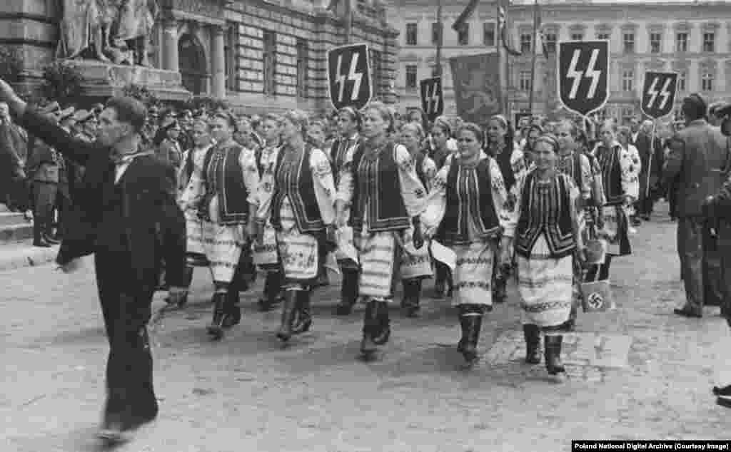 Ukrainian women in traditional clothing parade under Nazi banners in Lviv during an official visit by Hans Frank, the German ruler of Nazi-occupied Poland.&nbsp; Many Ukrainian nationalists took an &quot;enemy of my enemy is my friend&quot; stance to the Nazi invasion, crediting the Germans with driving out the communist Bolsheviks. Some Ukrainians actively participated in the mass killings of Jews, while others, &quot;individuals and sometimes entire villages,&quot; risked everything to shelter Jews from the Nazis.