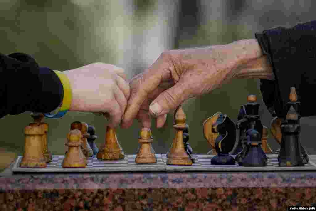 An elderly man teaches a boy to play chess in Taras Shevchenko Park in Kyiv.