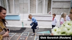 First-graders play near a school before a ceremony to mark the start of the new school year in Kyiv on September 1.