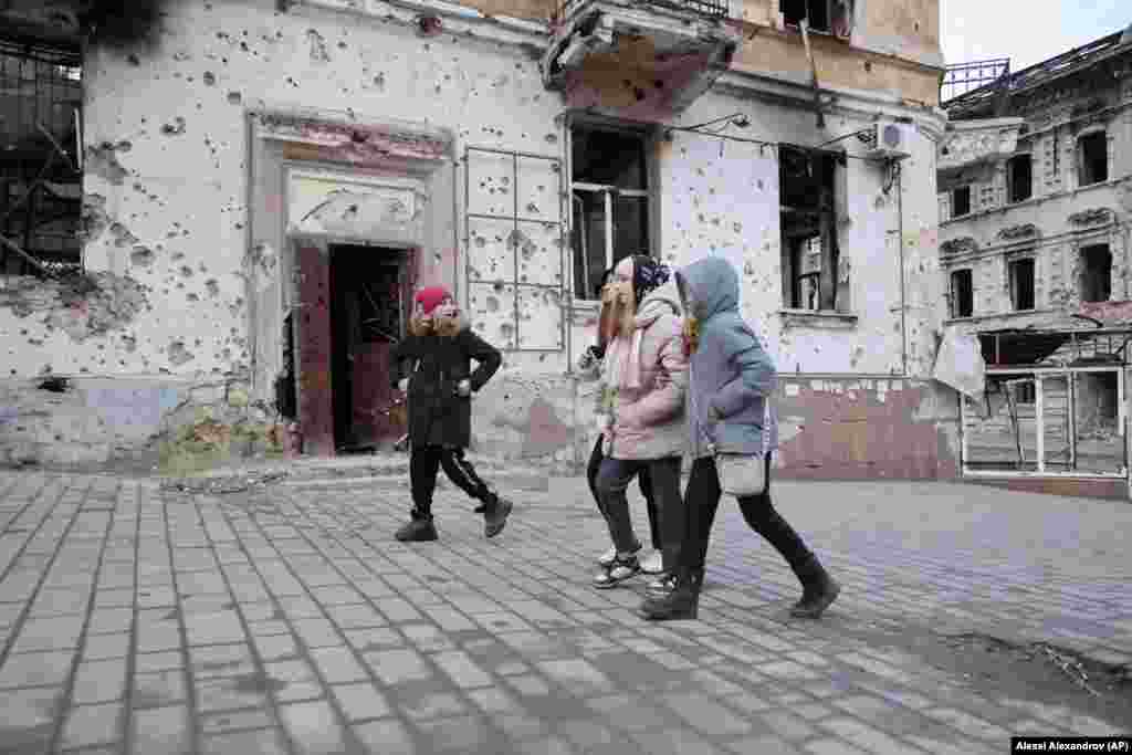 Children pass shrapnel-scarred buildings in Mariupol on February 25, 2023. Thousands of civilians were killed during the Russian siege. Russia claims 3,000 civilians were killed, while Kyiv claims that more than 25,000 died.