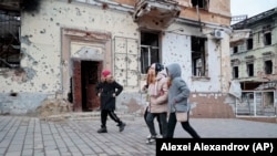 Подростки гуляют по Мариуполю через 10 месяцев после того, как город захватила российская армия. Февраль 2023 года