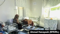 یک بانو نشسته در کنار طفل بیمار خود در شفاخانه ولایت پنجشیر