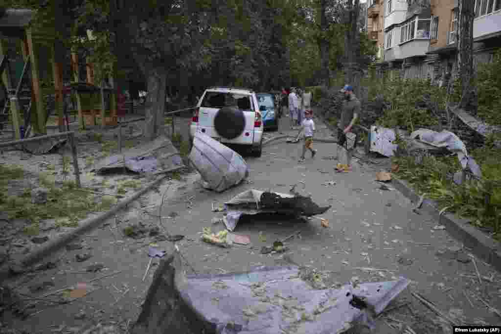 Local residents pass by debris in Kyiv that fell down from their damaged house after a massive Russian rocket attack on the Ukrainian capital on August 30.&nbsp;