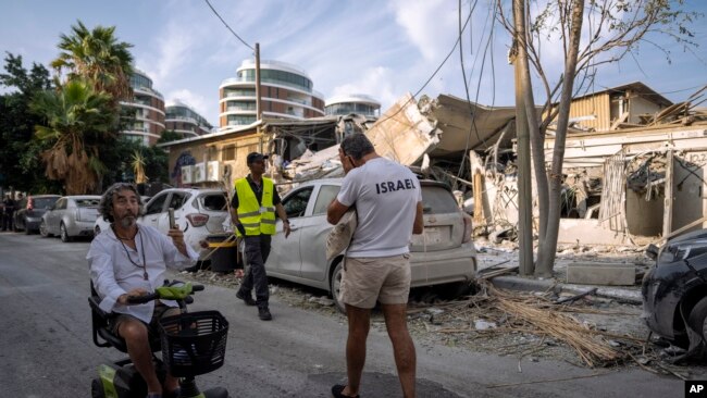 Израелците ги проверуваат урнатините на зградата еден ден откако беше погодена од ракета истрелана од Појасот Газа, во Тел Авив, Израел, недела, 8 октомври 2023 година.