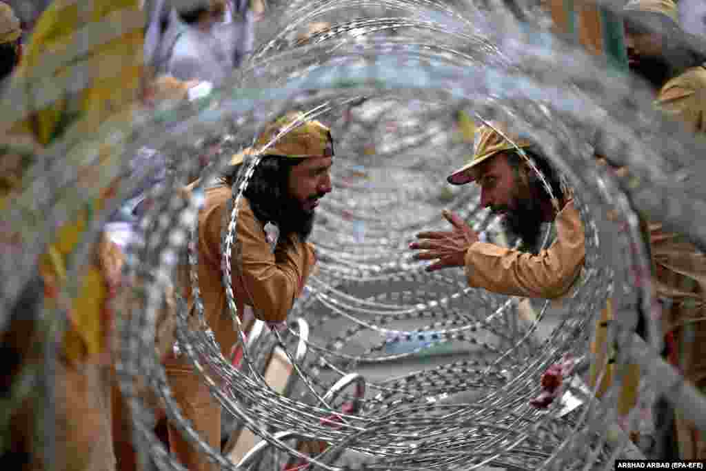 Security personnel of the Islamic political party Jamiat Ulema-e-Islam JUI talk during a protest against alleged rigging in the general elections, in Peshawar, Pakistan.