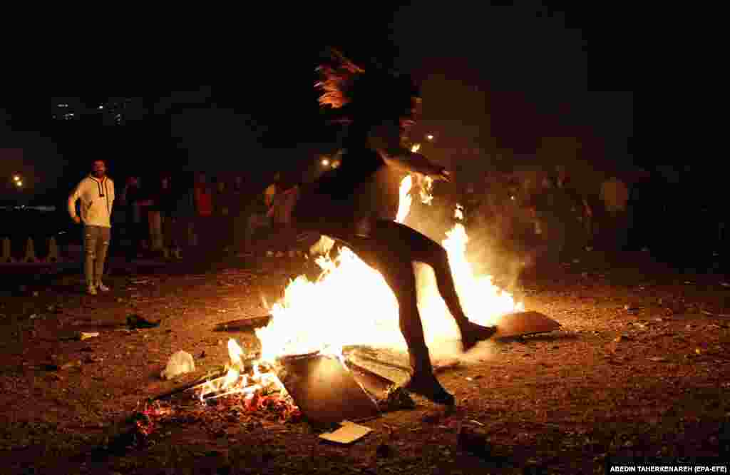 An Iranian girl without a head scarf jumps over a fire during a traditional fire feast called Charshanbeh Suri in Tehran.