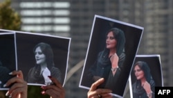 Protesters hold up photos of Mahsa Amini at a protest following her death in police custody.