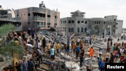 Palestinieni adunați în jurul ruinelor unor clădiri bombardate de armata israeliană, în 9 octombrie.