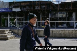 Tsuchiko walks past war-damaged buildings in Kharkiv.