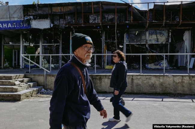 Tsuchiko duke ecur pranë ndërtesave të dëmtuara nga lufta në Harkiv.
