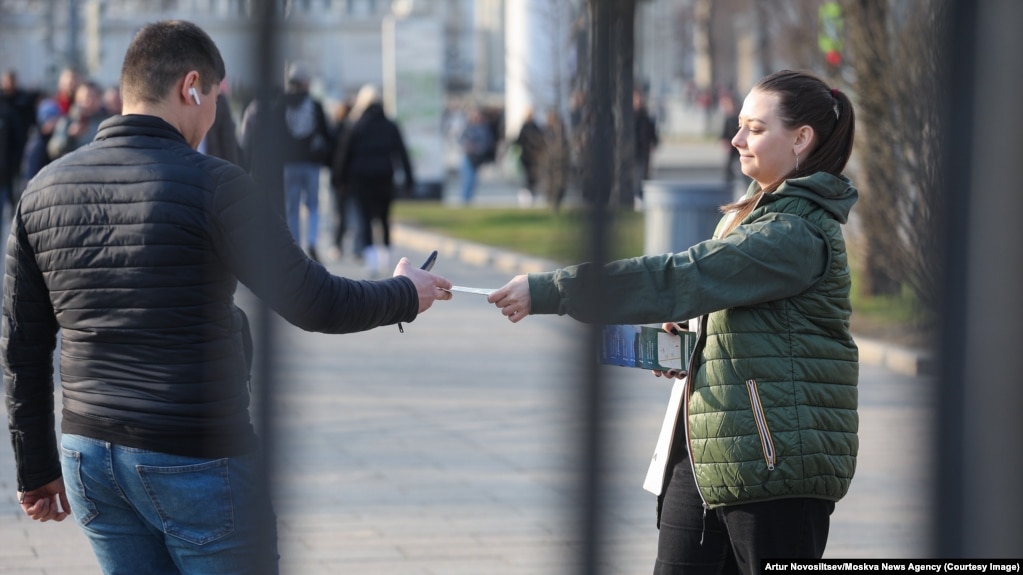 A woman in Moscow hands out leaflets calling on people to join the Russian Army.