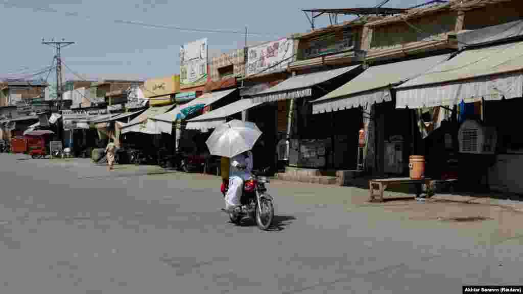 Napernyős motorkerékpározás&nbsp;Dzsakobabad egyik kihalt piacán. Az emelkedő hőmérséklet miatt Pandzsábban bezárták az iskolákat, ami legalább huszonhatmillió gyermeket érint