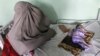 An Afghan woman sits next to a child suffering from malnutrition and other diseases while receiving treatment at Mirwais hospital in Kandahar.