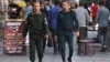 Two policemen walk through Tehran on July 16. The officer on the left is wearing the standard green uniform&nbsp;<strong><a href=https://www.rferl.org/p/