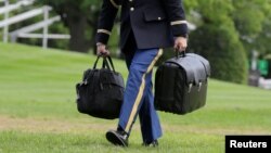 Vojni pomoćnik u Bijeloj kući nosi kofer i torbu u u kojoima se nalaze šifre za nuklearno oružje za vrijeme mandata predsjednika Bakacka Obame, maj 2016. 