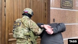 Сотрудник ФСБ России ведет задержанного крымчанина в управление ФСБ в Крыму. Симферополь, декабрь 2023 года